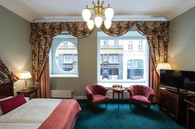 a bedroom with a bed and two chairs and a window at Hotel Liberty in Prague