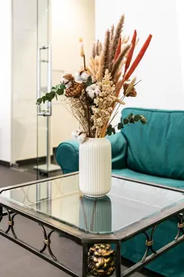 a vase with flowers on a glass table in a living room at My Hotel Apollon in Prague