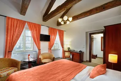 a bedroom with a bed and a desk and chairs at Hotel Lippert in Prague