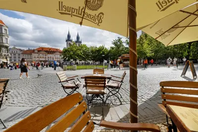 an outdoor cafe with tables and chairs in a city square at Hotel Lippert in Prague