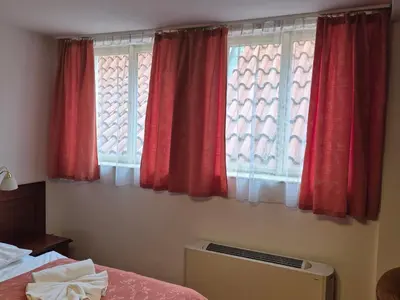 a bedroom with two windows with red curtains at Hotel Lippert in Prague