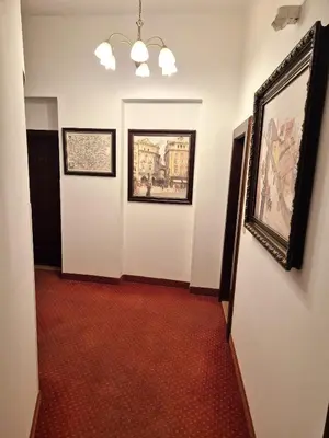 a hallway with a red carpet and paintings on the walls at Hotel Lippert in Prague
