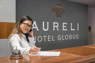 a woman sitting at a table talking on a cell phone at Hotel Globus in Prague