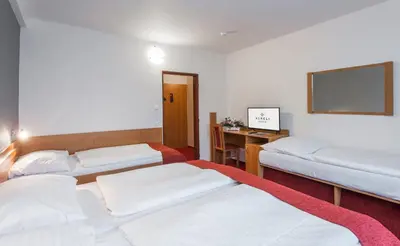 a hotel room with three beds and a desk at Hotel Globus in Prague