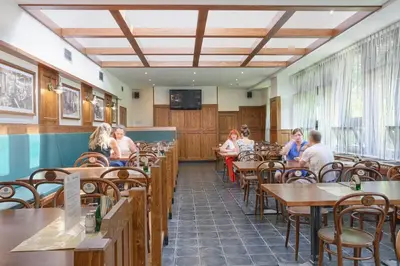 a group of people sitting at tables in a restaurant at Hotel Globus in Prague