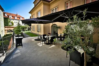 a patio with tables and chairs and umbrellas at Appia Hotel Residences in Prague