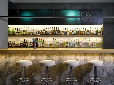 a bar with stools in front of a shelf of bottles at The ICON Hotel in Prague
