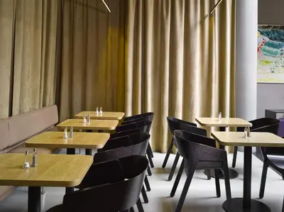 a restaurant with wooden tables and chairs and curtains at The ICON Hotel in Prague