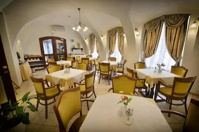a restaurant with tables and yellow chairs and a room at Hotel Certovka in Prague