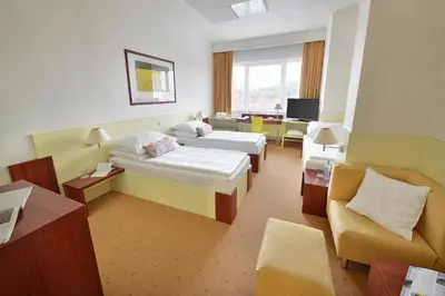 a hotel room with two beds and a couch at Hotel Grand Litava Beroun in Beroun