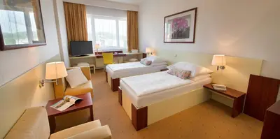 a hotel room with two beds and a desk at Hotel Grand Litava Beroun in Beroun