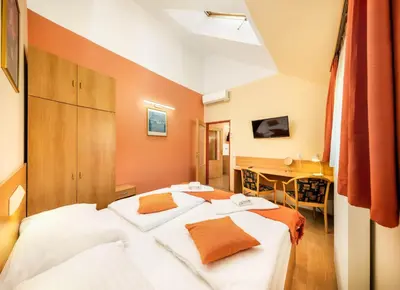 two beds in a hotel room with a desk at Residence Tabor in Prague