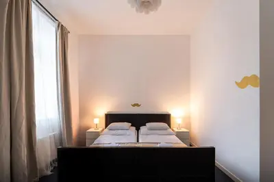 a bedroom with two beds and a window and two lamps at Little Tom Apartments in Prague