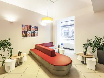 a waiting room with a red couch and two tables at Ibis Praha Old Town in Prague
