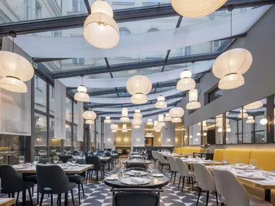 a dining room with tables and chairs and chandeliers at Century Old Town Prague - MGallery Collection in Prague