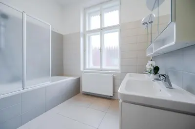 a white bathroom with a sink and a bath tub at Hotel U 3 Pstrosu in Prague