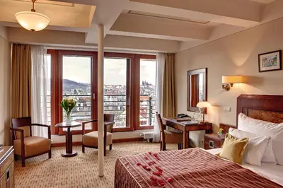 a hotel room with a bed and a desk and a window at Majestic Plaza Hotel Prague in Prague