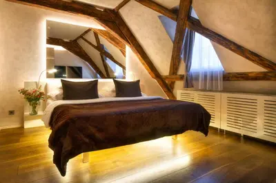 a bedroom with a large bed in a room with beams at Three Storks in Prague