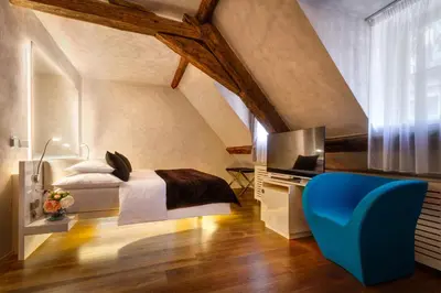 a bedroom with a bed and a blue chair at Three Storks in Prague