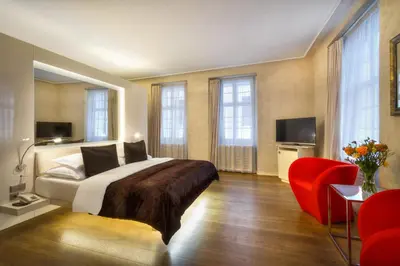 a bedroom with a bed and a red chair at Three Storks in Prague