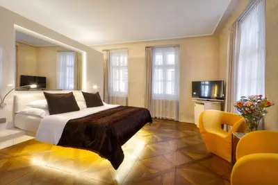 a bedroom with a bed and a couch and windows at Three Storks in Prague