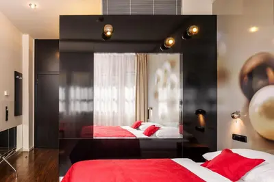 a bedroom with two beds with red sheets and a mirror at Perla Hotel in Prague