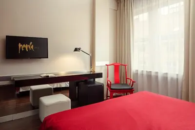 a bedroom with a desk and a red bed at Perla Hotel in Prague