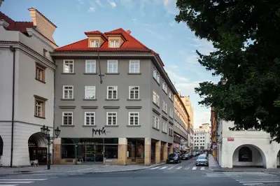 a large white building with a red roof on a street at Perla Hotel in Prague