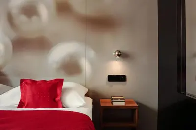 a room with a bed with a red pillow and a table at Perla Hotel in Prague