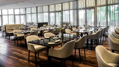 a dining room with tables and chairs and windows at NH Prague City in Prague