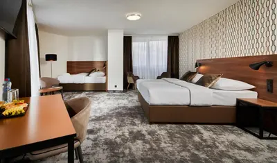 a hotel room with a large bed and a desk at OREA Hotel Pyramida Praha in Prague