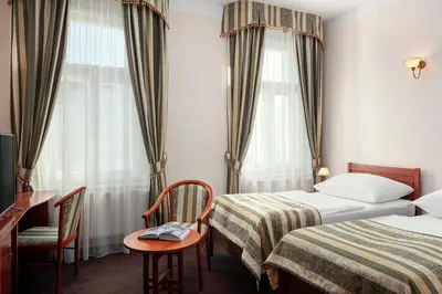 a hotel room with two beds and a table and chairs at Amigo City Centre in Prague