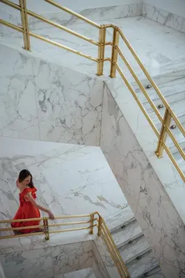 a woman in a red dress walking down a marble staircase at Almanac X Alcron Prague in Prague