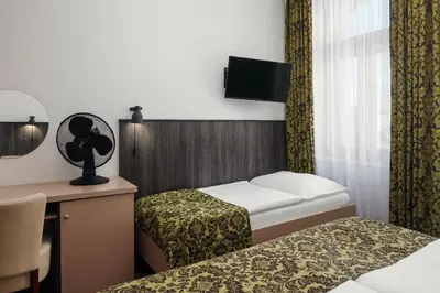 a room with two beds and a desk and a tv at Hotel Superior Prague in Prague