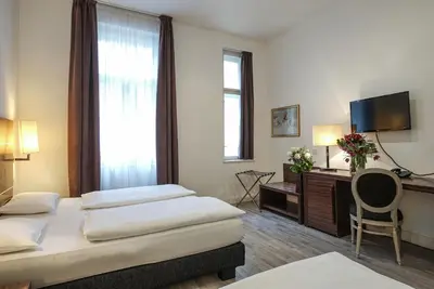 a hotel room with two beds and a television at Hotel Assenzio Prague in Prague