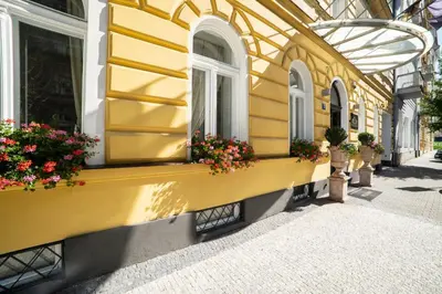 a yellow building with flowerpots and windows on a street at Hotel Assenzio Prague in Prague