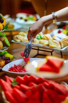 a person holding a spatula over a plate of fruit at Charles Central in Prague