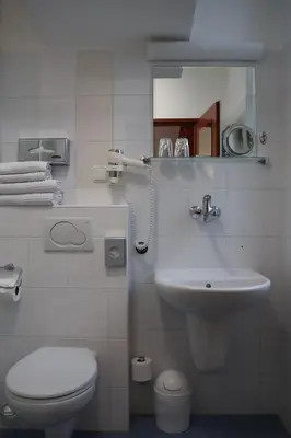a white bathroom with a toilet and a sink at Unitas Residence in Prague