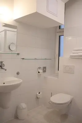 a white bathroom with a toilet and a sink at Unitas Residence in Prague