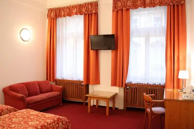 a hotel room with a bed and a chair and a television at Unitas Residence in Prague