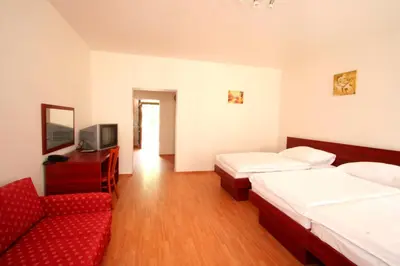 a hotel room with two beds and a red couch at Apart Hotel Susa in Prague