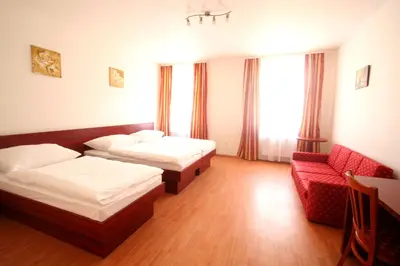 a hotel room with two beds and a red couch at Apart Hotel Susa in Prague