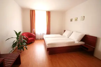 a bedroom with a bed and a chair and a window at Apart Hotel Susa in Prague