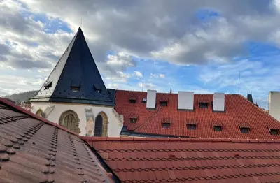 a church with a steeple on top of a roof at Hotel King George in Prague