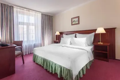 a hotel room with a large white bed and a window at Hotel Lunik in Prague