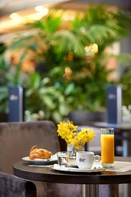 a table with a plate of food and a cup of orange juice at Congress & Wellness Hotel Olsanka in Prague