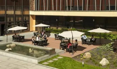 a group of people sitting at tables with umbrellas at Congress & Wellness Hotel Olsanka in Prague