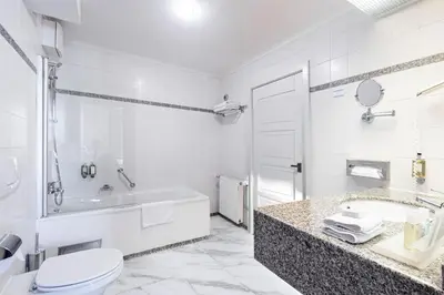 a white bathroom with a tub and a toilet and a sink at Grand Hotel International - Czech Leading Hotels in Prague