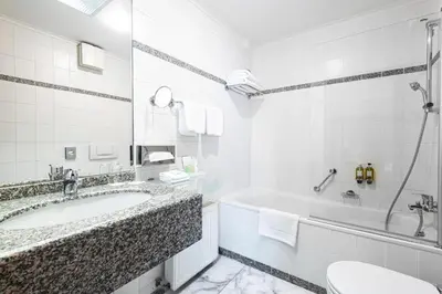 a white bathroom with a tub and a sink at Grand Hotel International - Czech Leading Hotels in Prague