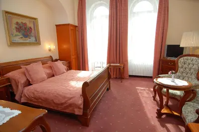 a hotel room with a bed and a table and chairs at Hotel Opera in Prague